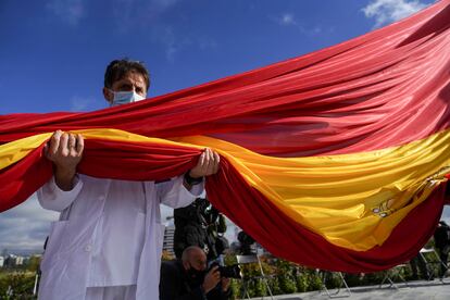 El jefe de la UCI del hospital Infanta Sofía sostiene la bandera de 75 metros cuadrados izada este viernes en Valdebebas.