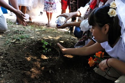 Algunos niños que acudieron a ver la ceremonia riegan una planta y realizan una ofrenda floral como muestra de compromiso con el cuidado del medio ambiente.