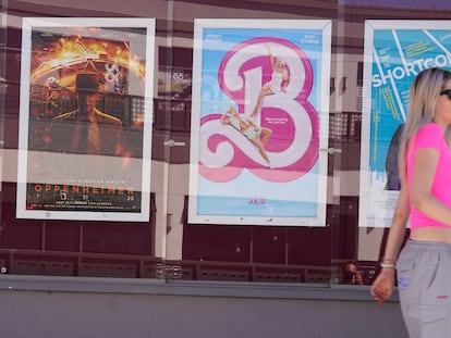 A woman walks past advertisements for the films "Oppenheimer," from left, and "Barbie," on Thursday, July 20, 2023, at the Landmark Theater in Los Angeles.