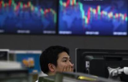 Un empleado de la Bolsa de Seúl trabaja junto a varios monitores que muestran la evolución del índice Kospi.