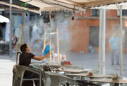 Una mujer usa un abanico para refrescarse en una terraza de Sevilla, este lunes.
