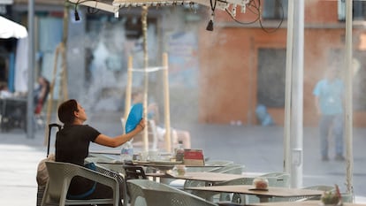 Una mujer usa un abanico para refrescarse en una terraza de Sevilla, este lunes.