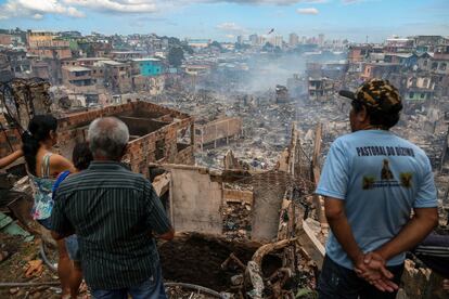 Dos vecinos observan los restos del barrio asolado por el incendio, el 18 de diciembre.
