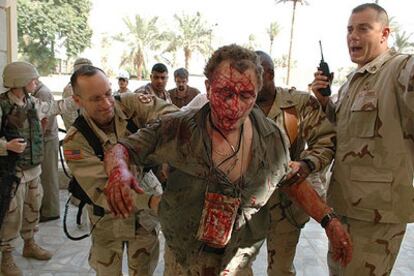 Soldados estadounidenses ayudan a un herido tras la explosión de dos bombas el jueves en la Zona Verde de Bagdad.