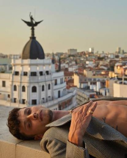 Tumbado sobre la Gran Vía, Ayax viste americana de cuadros Emporio Aarmani.