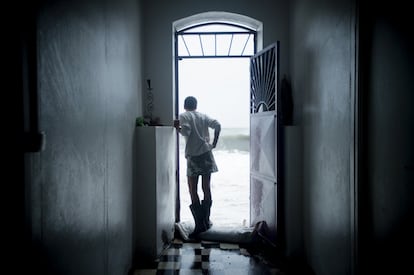 Un residente de la isla de Martinica observa las fuertes olas producidas por el huracán María desde la puerta de su casa.