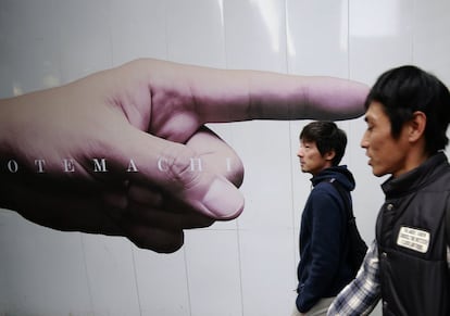 Men pass advertisements posted on the fence of a construction site in Tokyo's Otemachi business district Monday, Nov. 7, 2016. (AP Photo/Shizuo Kambayashi)