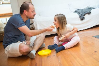 Un padre comparte un sandwich de jamón y queso con su hija.