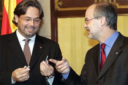 Ernes Benach, a la izquierda, sostiene la copia de los presupuestos de la Generalitat en formato digital que le acaba de entregar Antoni Castells.