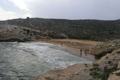 El parque regional de Calblanque es célebre por sus playas, aunque mucho menos por esta calita de campanillas encastrada entre Punta Espada y Punta Negra. Cala Déntoles —o cala Dorada— cobra un valor inusitado por su variedad cromática: del negro en los restos mineros al dorado en la arena. Y además lirios marinos (en floración primaveral), cornicales y algún palmito. Al pie del cerro del Atalayón sorprendemos a un pintor con su caballete retratando la bella escena. El baño, como en toda esta franja de costa abierta al levante, entraña peligros, por lo que hay que ir con tiento. Al regreso, el mirador de Punta Negra ya forma parte del imaginario colectivo costero de Murcia. <p><b>Acceso:</b> en Calblanque, tras rebasar las salinas, aparcamos en cala Magre. A 600 metros, después de un repecho, alcanzamos los Déntoles. A partir de junio solo se puede acceder en autobús público. El sendero desde cala Reona (unos 2 kilómetros) cuenta con un tramo complicado con cuerdas para sujetarse.</p>