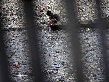 Una persona recoge residuos en un río contaminado en Yakarta (Indonesia).