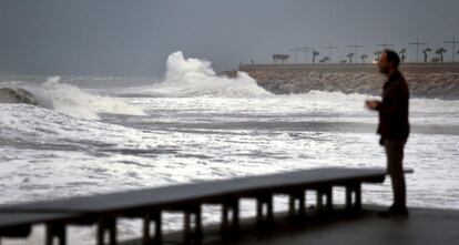 Un hombre mira como las olas rompen en las rocas del paseo marítimo de Torrevieja (Alicante), dentro del temporal de lluvia y viento que azota el sudeste de la Península ibérica, el 18 de diciembre de 2016.