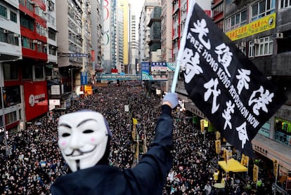 Manifestante mascarado ergue faixa em Hong Kong, neste domingo.