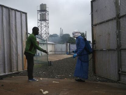 Un trabajador sanitario rocía a un posible enfermo de ébola a la entrada de un centro de tratamiento de Monrovia (Liberia).