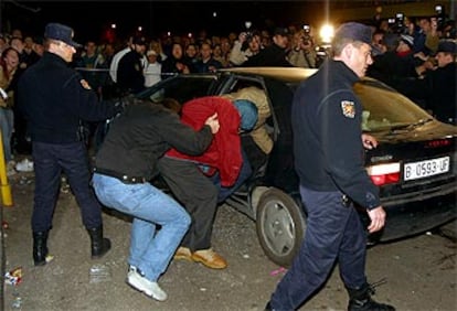 La policía introduce al detenido en un vehículo tras participar en el registro de su domicilio.