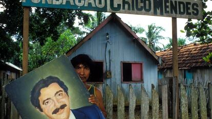 Un joven sostiene una pintura con el retrato de Chico Mendes, defensor de la Amazonía asesinado hace tres décadas.