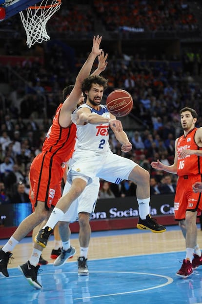El base del Real Madrid, Sergio Llull (2I), pasa un balón ante la defensa del pivot montenegrino del Valencia Basket, Bojan Dubljevic.