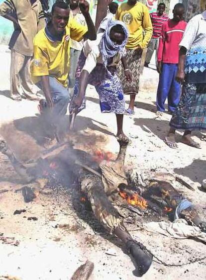 Unos somalíes golpean el cadáver quemado de un soldado gubernamental ayer en Mogadiscio.