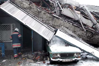 Un miembro de un equipo de rescate pasa junto a un coche aplastado por los escombros. El mercado Basmanny se derrumb a primera hora del jueves. El edificio se construy en la dcada de los 70.