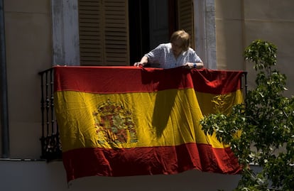 Una mujer coloca una bandera en la plaza de Oriente, junto al Palacio Real.