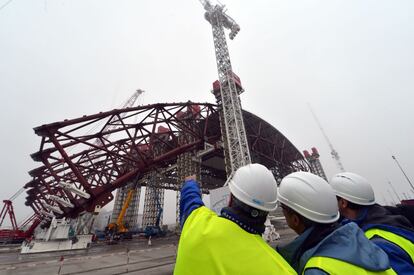 Trabajadores observan la instalación de la primera parte del sarcófago que cubrirá el reactor centrar de Chernóbil que estalló en 1986.