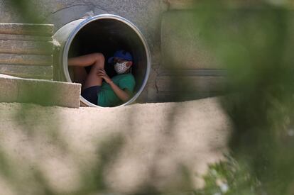 Un joven protegido por una mascarilla se resguarda del calor en el interior de una tubería en la zona de Madrid Río, durante una jornada de intenso calor registrado en la capital.