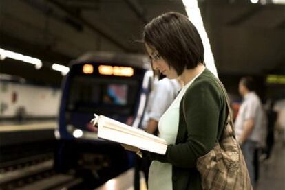 Una viajera del metro leyendo en el andén de una estación.