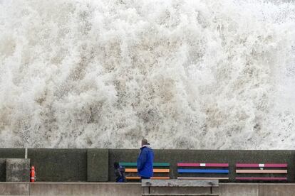 Un hombre y su hijo observan las olas creadas por los fuertes vientos y las mareas vivas que golpean el malecón en el paseo marítimo de New Brighton, en Liverpool (Inglaterra).
