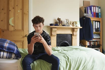 Un joven mira el móvil en su habitación. 