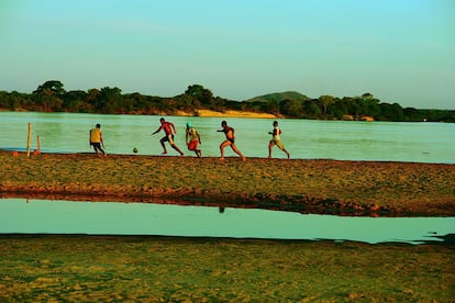 No interior do estado do Pará e às margens do Rio Araguaia, cinco rapazes correm atrás da bola para marcar um gol, delimitado por dois bambus.