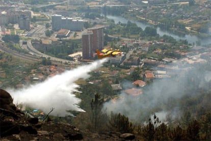 Un hidroavión vierte agua sobre varios puntos de fuego cerca del barrio orensano de O Pino.