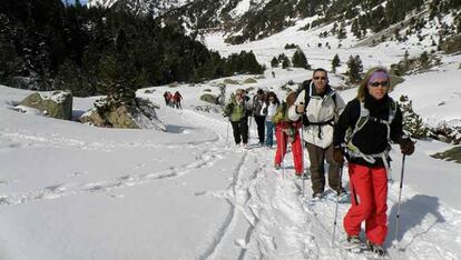 Excursionistas con raquetas de nieve, en la sierra de Madrid, realizando una ruta organizada por Amadablam Aventura.