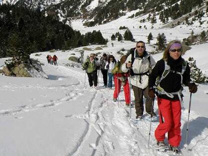Excursionistas con raquetas de nieve, en la sierra de Madrid, realizando una ruta organizada por Amadablam Aventura.