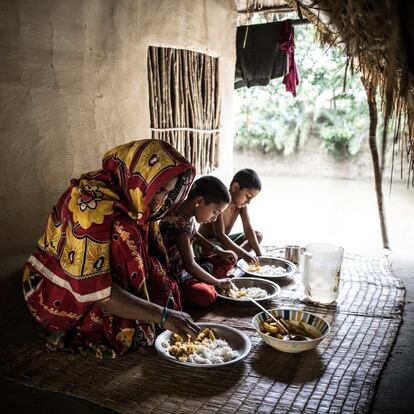 Rexona Begum, de 30 años, es la madre de Sumiya Mullah, de cinco, y Moriom Mullah, de seis. Están comiendo patatas al curry y arroz en la aldea de Kultoli, en Bangladesh, el 3 de abril de 2016. Sumiya ha sido diagnosticado de malnutrición. Rexona hace todo lo posible para mantener a sus hijos, pero muchas necesidades básicas están fuera de su alcance. La familia posee su propia casa, pero no tienen tierras ni medios para proporcionar diversos alimentos a sus hijos. Gracias al asesoramiento de la clínica local, ha comenzado a incorporar más verduras en su cocina, a menudo recogiendo el tipo de vegetales de hoja verde que los vecinos descartan porque los ven poco atractivos . Aún así, muchas de las recomendaciones de nutrición de la clínica son imposibles para ella.