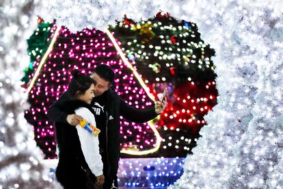 A man kisses his partner as they take a selfie near light installation decorated for the Christmas season outside an office building in Beijing, Thursday, Dec. 1, 2016. Although Christmas is not traditionally celebrated in China, some office buildings and shopping malls welcome the festival with colorful decorations. (AP Photo/Andy Wong)