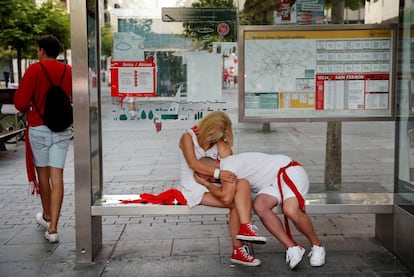 Una pareja descansa en una parada de autobús durante las fiestas en Pamplona, el 12 de julio de 2019.