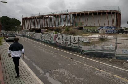 Un hombre pasa junto a las ruinas del Centro Internacional de Estudios Económicos y Sociales en Majadahonda.