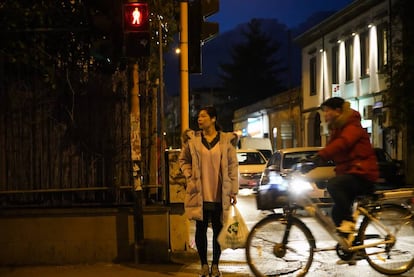 Una mujer china espera en un cruce del barrio chino de Prato.