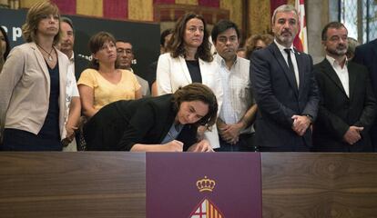 La alcaldesa de Barcelona, Ada Colau, acompa&ntilde;ada de autoridades, firma en el libro de condolencias abierto en el Ayuntamiento.  