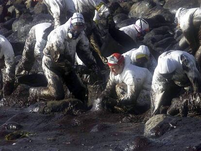 Voluntarios recogen chapapote en cabo Touri&ntilde;&aacute;n en diciembre de 2002.