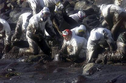 Voluntarios recogen chapapote en cabo Touri&ntilde;&aacute;n en diciembre de 2002.