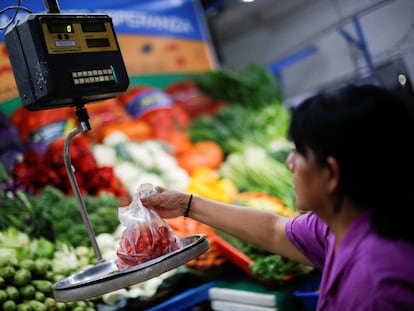 Una vendedora de vegetales pesa tomates en un mercado en Buenos Aires, el pasado 14 de marzo.