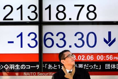 Un peatón espera su turno para cruzar ante una pantalla que muestra información bursátil en Tokio (Japón).