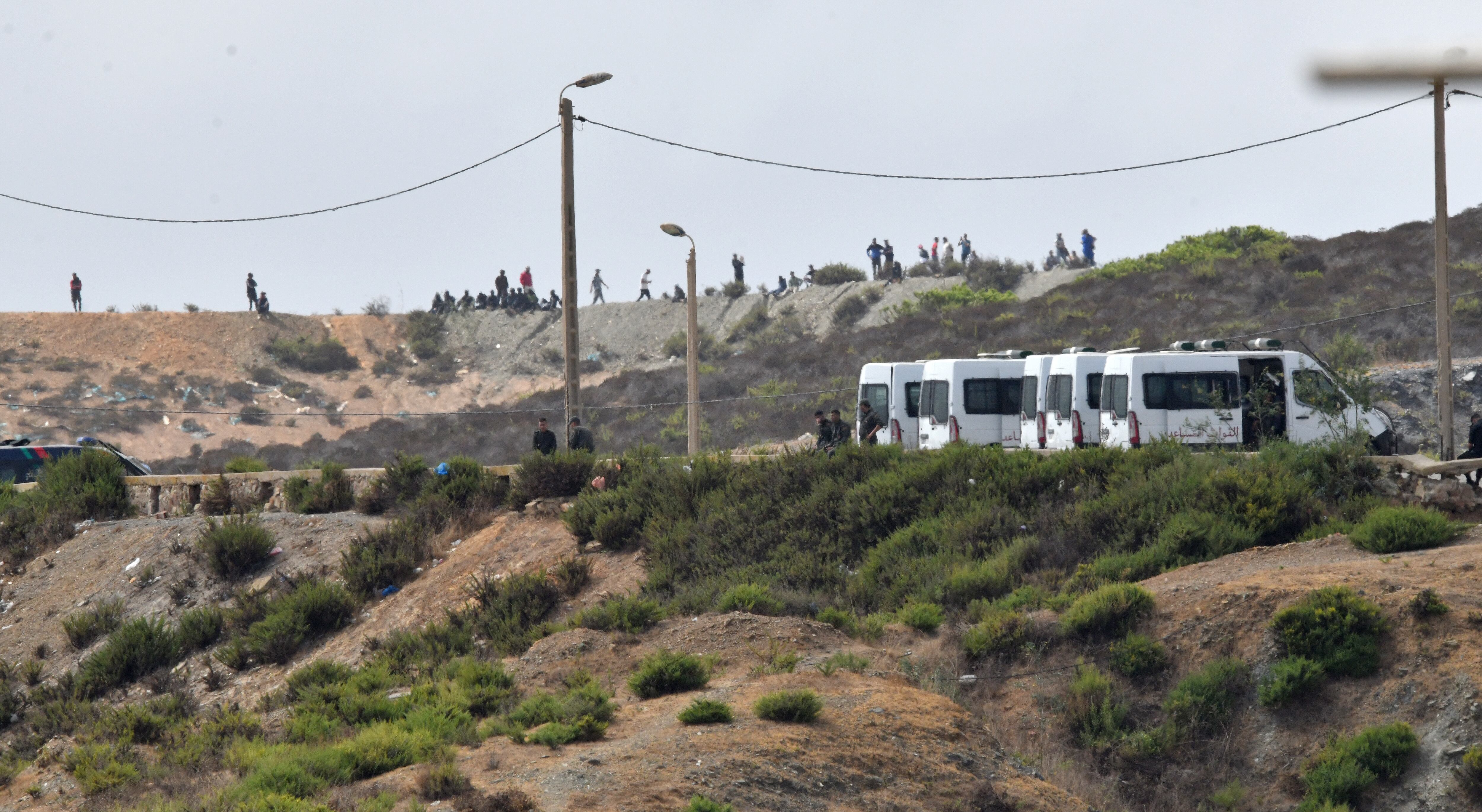 Centenares de personas se congregan en un monte cercano a la frontera con Ceuta para intentar cruzar a la ciudad española, este domingo.