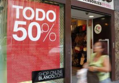 Una mujer pasa por delante de una tienda de moda en Madrid que anuncia las rebajas de verano. EFE/Archivo