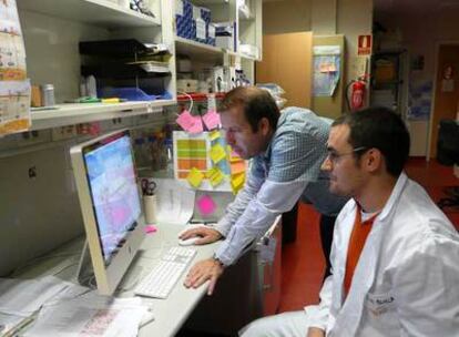 Jesús Molina, con la camisa de cuadros, y un investigador, en el CNIO de Madrid.