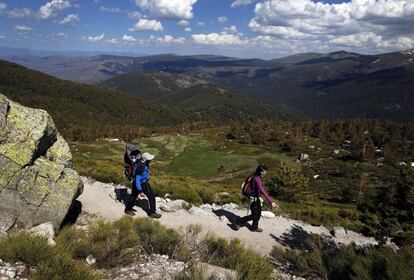 Los excursionistas visitan las inmediaciones de Peñalara y van dejando la inmensidad del Valle del Lozoya a su izquierda.