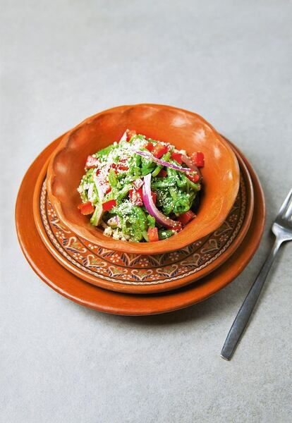 <p><i>Región: Distrito Federal, Tlaxcala</i></p><p><b> Ingredientes</b></p><p> Para 6 personas: una cucharada y un tercio de sal marina, una pizca de bicarbonato, 600 gramos de nopales cortados en tiras, 4 cucharadas de cilantro picado, un tomate picado, una cebolla roja pequeña cortada en rodajas finas y un poco más para servir, 4 cucharadas de aceite de oliva virgen extra, una cucharadita de orégano seco, un tomate cortado en dados. Para servir: 120 gramos de queso parmesano rallado. </p><p><b> Preparación</b></p><p> <i> Preparación: 45 minutos. Cocción: 25 minutos.</i></p><p> 1. Llevar a ebullición una olla con agua. Salar, añadir el bicarbonato y los nopales, y cocerlos 20 minutos, hasta que estén tiernos pero sin perder consistencia. 2. Retirar la olla del fuego, escurrirlos bien y refrescarlos en agua fría hasta que dejen de estar viscosos. 3. Volver a escurrir. Mezclarlos con una cucharadita de sal, el cilantro, el tomate, la cebolla y el aceite de oliva en un bol grande. Añadir el orégano, desmenuzándolo entre las palmas de las manos o con los dedos. Dejarlos reposar unos minutos. 4. Colocar la ensalada en una fuente y disponer encima los dados de tomate. Adornarla con queso rallado y rodajas de cebolla, y servir.</p>