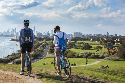 Dos ciclistas en Point Ormond, con el perfil urbano de Melbourne al fondo.
