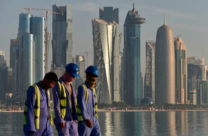 Los trabajadores tienen como telón de fondo el horizonte de Doha, capital de Qatar, mientras caminan por el paseo marítimo de la ciudad, el 17 de noviembre, antes del inicio de la Copa Mundial de Qatar 2022.